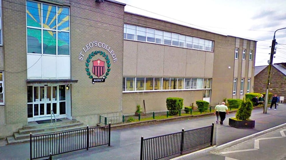Gebäudefassade mit großem Logo der St. Leo’s College und eine Person auf dem Gehweg im Hintergrund.