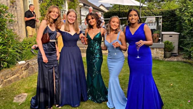 Eine Gruppe junger Schülerinnen in festlicher Kleidung posiert im Garten auf dem Campus von St. Leo’s College.