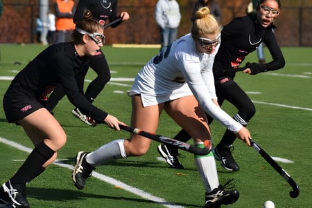 Schülerinnen und Schüler des St. Leo’s College spielen ein Feldhockeyspiel auf dem grünen Rasen.