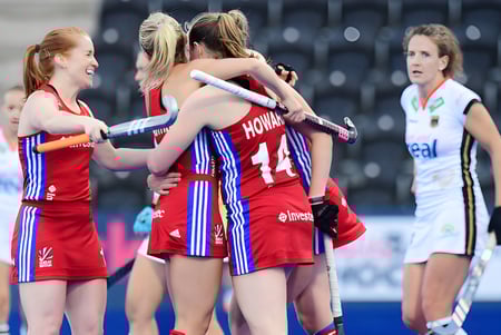 Eine Gruppe von Athletinnen der St. Louis Community School umarmt sich auf dem Sportfeld während eines Spiels.