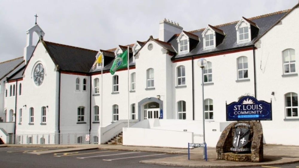 Das mehrstöckige weiße Gebäude mit Uhrenturm und Flaggen auf dem Dach ist ein Teil der St. Louis Community School.