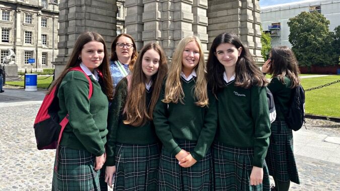 Eine Gruppe von Schülerinnen steht vor dem historischen Gebäude der St. Louis Community School auf einer grünen Wiese.