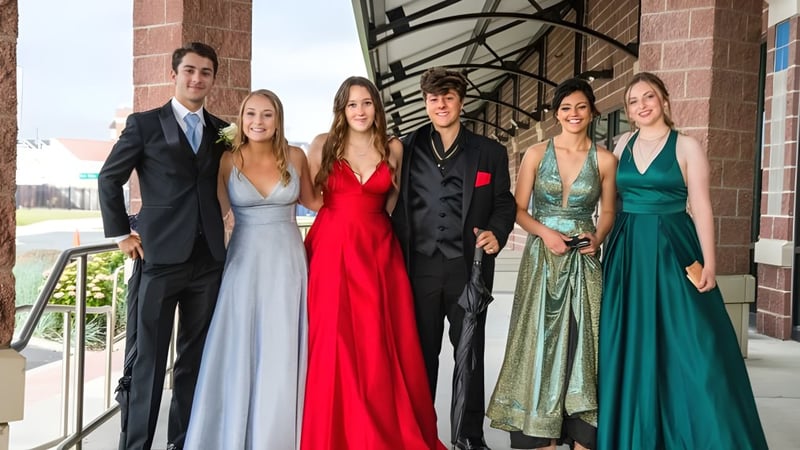 Sechs Schüler der St. Louis Community School in formeller Kleidung posieren vor einem Backsteingebäude mit architektonischen Details.