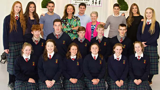 Eine Gruppe von Schülerinnen und Schülern der St. Louis Community School posiert gemeinsam in einem schulischen Raum vor dekorativen Pflanzen.