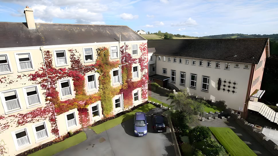 Der Innenhof der St. Louis Secondary School mit bunten mehrstöckigen Gebäuden und einer Grünfläche im Vordergrund.