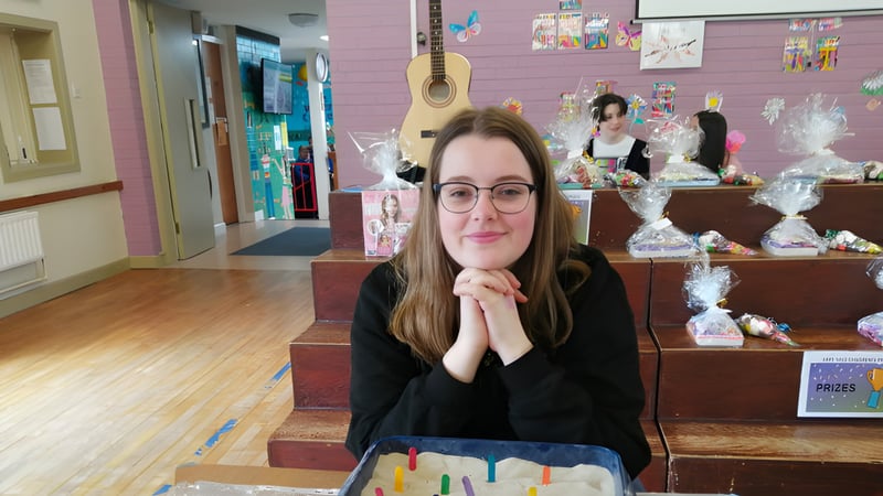 Eine Schülerin der St. Louis Secondary School sitzt nachdenklich in einem farbenfrohen, mit Kunstwerken gestalteten Raum.