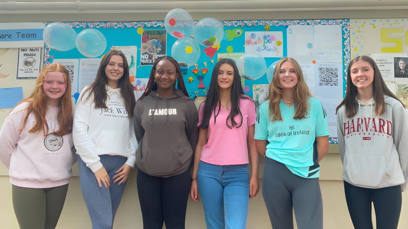 Sechs Schülerinnen stehen gemeinsam in einem farbenfrohen Klassenraum der St. Louis Secondary School.