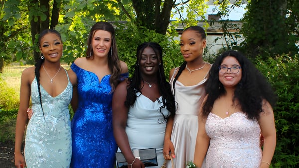 Eine Gruppe von fünf Schülerinnen steht auf dem Gelände der St. Louis Secondary School in Dundalk inmitten grüner Natur.