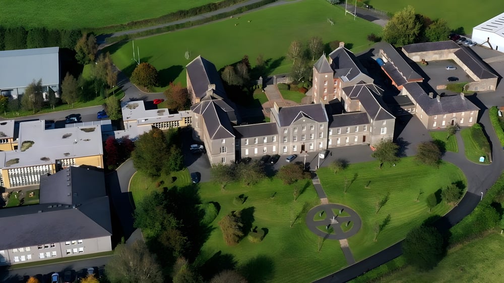 Ein großes historisches schlossähnliches Gebäude steht auf einem grasbewachsenen Hügel auf dem Campus von St. Macartan's College.