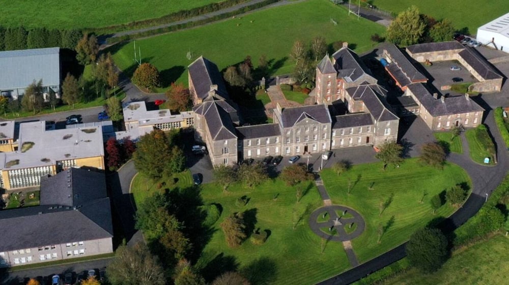 Das Schlossartige Hauptgebäude von St. Macartan's College steht auf einem grasbewachsenen Hügel mit umliegender grüner Landschaft.