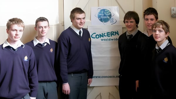 Eine Gruppe Schülerinnen und Schüler steht vor dem Banner von CONCERN worldwide auf dem Campus von St. Macartan's College.