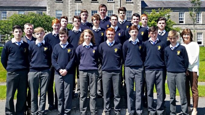 Schüler in Schuluniformen stehen vor einem historischen Gebäude auf dem Gelände von St. Macartan's College.