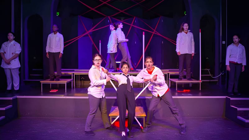 Schüler der St. Margaret’s School führen auf der Bühne eine Theater- oder Musikproduktion mit bunter Beleuchtung und geometrischen Mustern im Hintergrund auf.