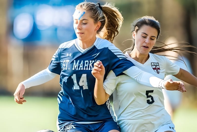 Zwei Fußballspielerinnen der St. Mark's School kämpfen auf einem Spielfeld um den Ball.