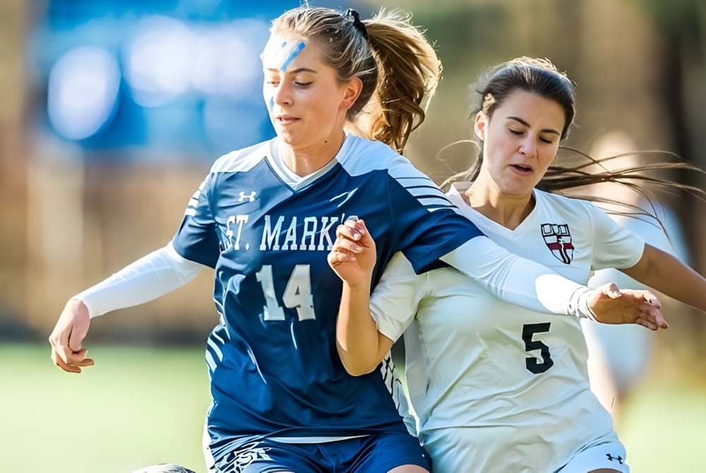Zwei Fußballspielerinnen der St. Mark's School kämpfen auf einem Spielfeld um den Ball.