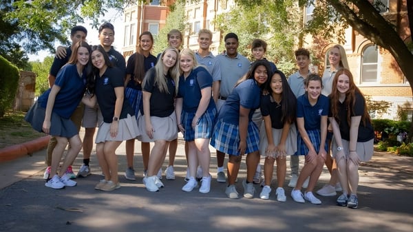 Eine Gruppe von Schülerinnen und Schülern steht gemeinsam draußen vor einem Backsteingebäude auf dem Campus der St. Mary Catholic High School.