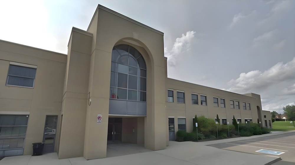 Das mehrstöckige Gebäude der St. Mary Catholic Secondary School mit einem hohen Bogen im Eingang und großen Fenstern vor bewölktem Himmel.