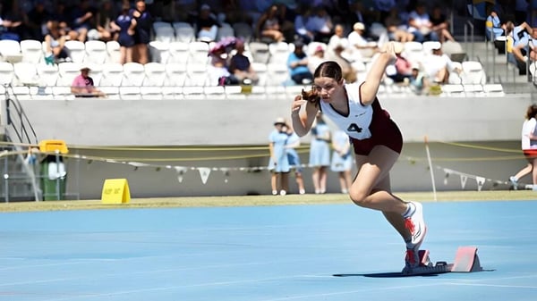 Eine Sportlerin der St. Mary's Anglican Girls' School führt eine Gymnastikübung auf einer blauen Matte vor Zuschauern aus.