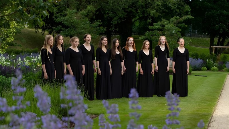 Eine Gruppe junger Frauen in schwarzen Talaren steht im blühenden Garten der St. Mary’s Calne.