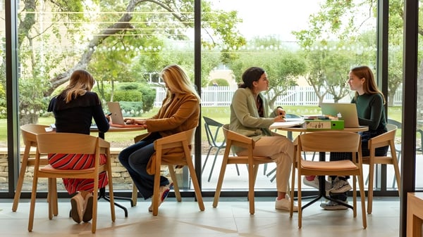 Eine Gruppe Schülerinnen der St. Mary’s Calne sitzt in einem gemütlichen Café mit großer Begrünung durch die Fenster.