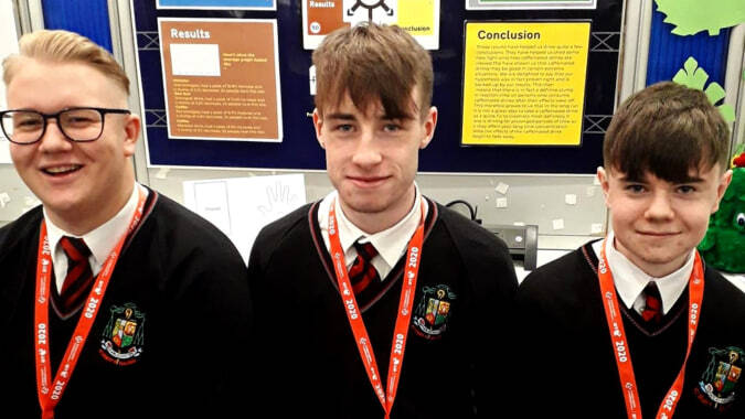 Drei Schüler in Schuluniform stehen vor einer Tafel mit Lehrmaterialien am St. Mary’s College Ballysadare.