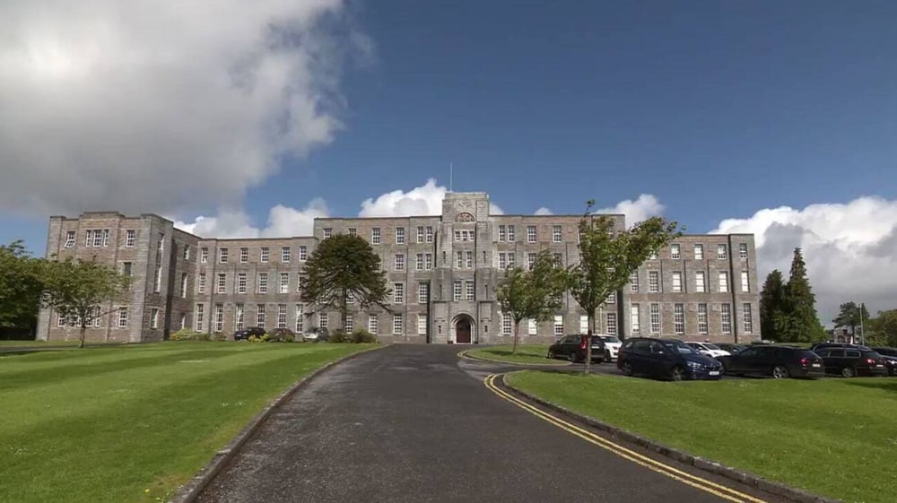 Das historische Hauptgebäude mit Turm des St. Marys College Galway ist umgeben von gepflegtem Rasen und Bäumen.