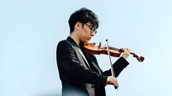 Ein junger Mann spielt Violine vor blauem Hintergrund auf dem Campus des St. Mary’s College.