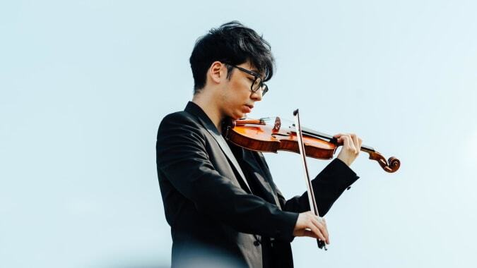 Ein Schüler des St. Mary’s College spielt Violine vor einem einfarbigen blauen Hintergrund.