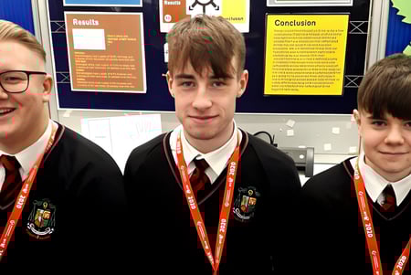 Drei Schülerinnen und Schüler in Schuluniform stehen vor einer Pinnwand auf dem Campus des St. Mary’s College Ballysadare.