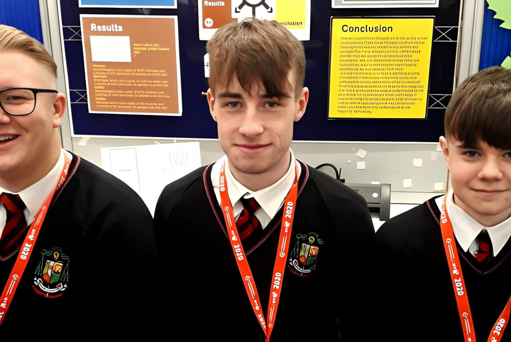 Drei Schülerinnen und Schüler in Schuluniform stehen vor einer Pinnwand auf dem Campus des St. Mary’s College Ballysadare.