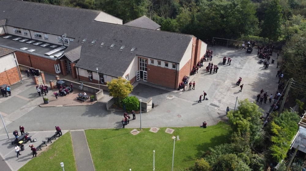 Menschen gehen über das Gelände vor dem Backsteingebäude auf dem Campus der St. Mary’s Diocesan School.