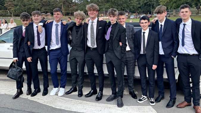 Eine Gruppe von Schülern in formeller Kleidung steht draußen auf dem Gelände der St. Mary’s Diocesan School vor Bäumen und Gebäuden.