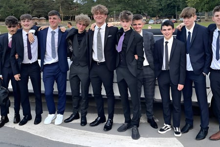 Eine Gruppe von Jungen in formeller Kleidung steht auf dem Außengelände der St. Mary’s Diocesan School mit Bäumen und Gebäuden im Hintergrund.