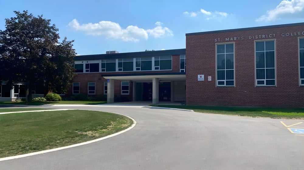 Das Backsteingebäude des St Mary’s District & Vocational Collegiate Institute ist von einem gepflasterten Weg und Grünflächen umgeben.
