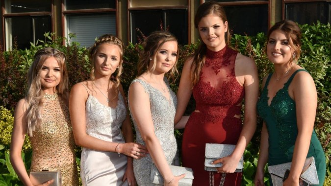 Fünf Schülerinnen in formeller Kleidung posieren vor grünem Hintergrund auf dem Campus der St. Mary's Holy Faith Killester.