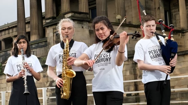 Eine Gruppe junger Musiker spielt vor dem klassischen Gebäude der St. Mary’s Music School verschiedene Instrumente.