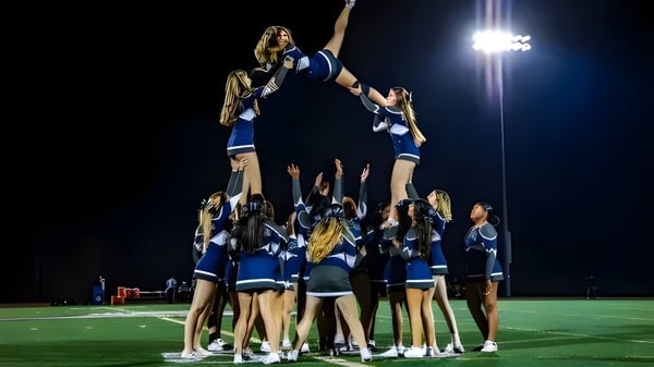 Schülerinnen und Schüler von St. Mary's Ryken High School bilden eine Cheerleader-Pyramide auf dem Footballfeld unter Flutlicht.