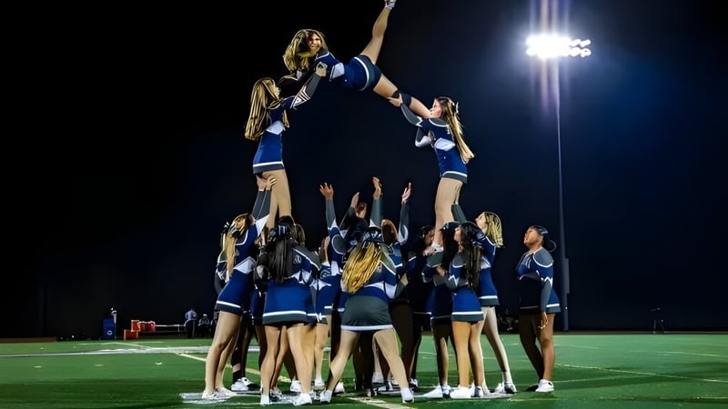 Schülerinnen und Schüler von St. Mary's Ryken High School bilden eine Cheerleader-Pyramide auf dem Footballfeld unter Flutlicht.