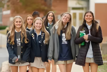 Eine Gruppe von Schülerinnen steht zusammen und lächelt auf dem Campus der St. Mary's Ryken High School.
