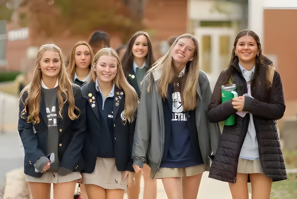 Eine Gruppe von Schülerinnen steht zusammen und lächelt auf dem Campus der St. Mary's Ryken High School.