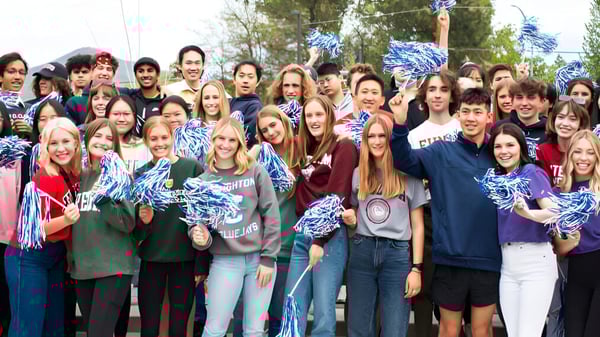 Schülerinnen und Schüler der St. Mary's School versammeln sich draußen mit blauen und weißen Pompons als Cheerleader-Team.