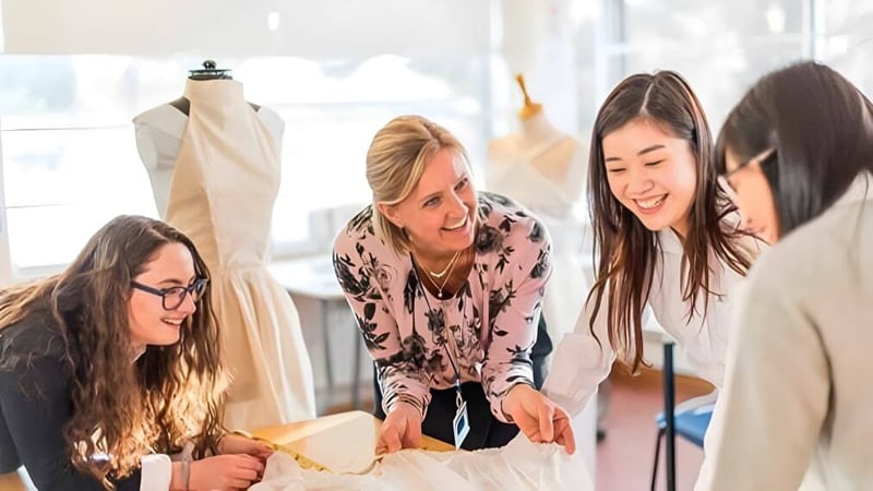 Schülerinnen der St. Mary's School arbeiten gemeinsam in einem Fashion Design Studio mit Nähmaschinen.