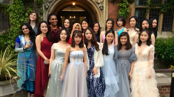 Eine Gruppe junger Frauen in formeller Kleidung steht vor dem historischen Backsteingebäude der St. Mary's School.