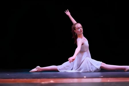 Eine Tänzerin in weißem Kleid führt eine Darbietung auf der Bühne der St. Mary's School auf.