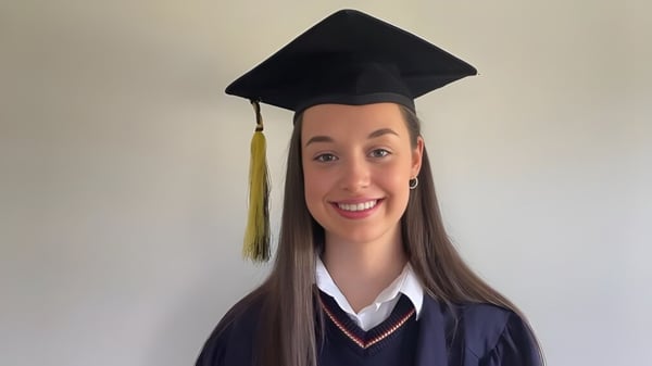 Eine Absolventin der St. Mary’s Secondary mit Abschlussmütze und -robe vor weißem Hintergrund.