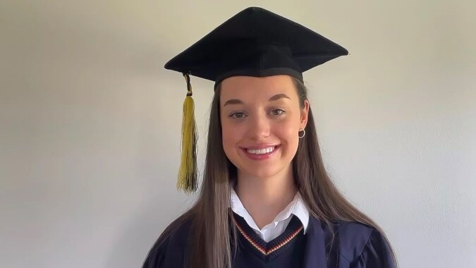 Eine Absolventin der St. Mary’s Secondary trägt eine Abschlussmütze und ein Abschlussgewand vor neutralem Hintergrund.