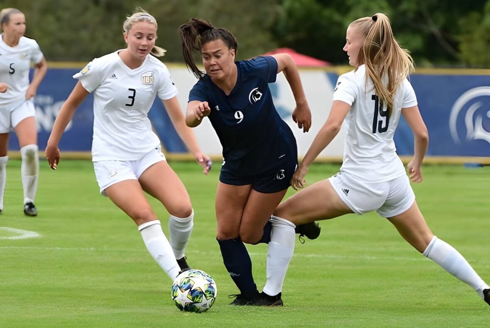 Drei Schülerinnen der St. Mary’s Secondary School Baldoyle konkurrieren um den Ball bei einem Fußballspiel auf dem Sportplatz.