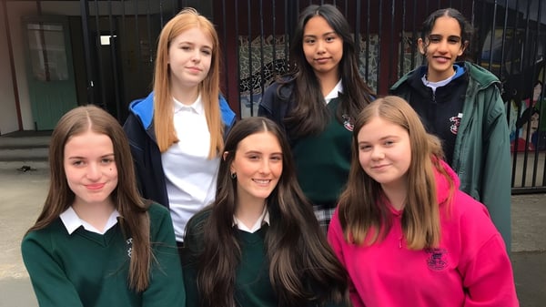 Eine Gruppe Schülerinnen steht vor einem Gebäude mit Metalltor auf dem Gelände von St. Mary's Secondary School in Charleville.