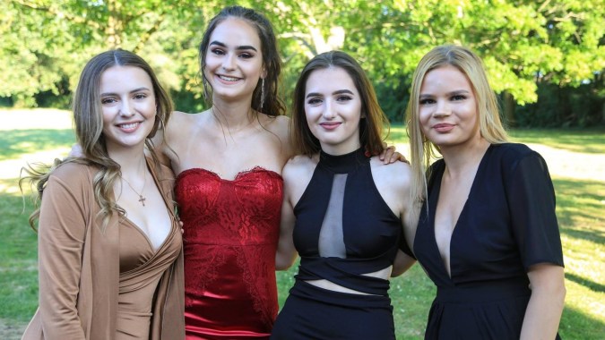 Vier Schülerinnen der St. Mary's Secondary School in formeller Kleidung posieren gemeinsam im grünen Außenbereich.