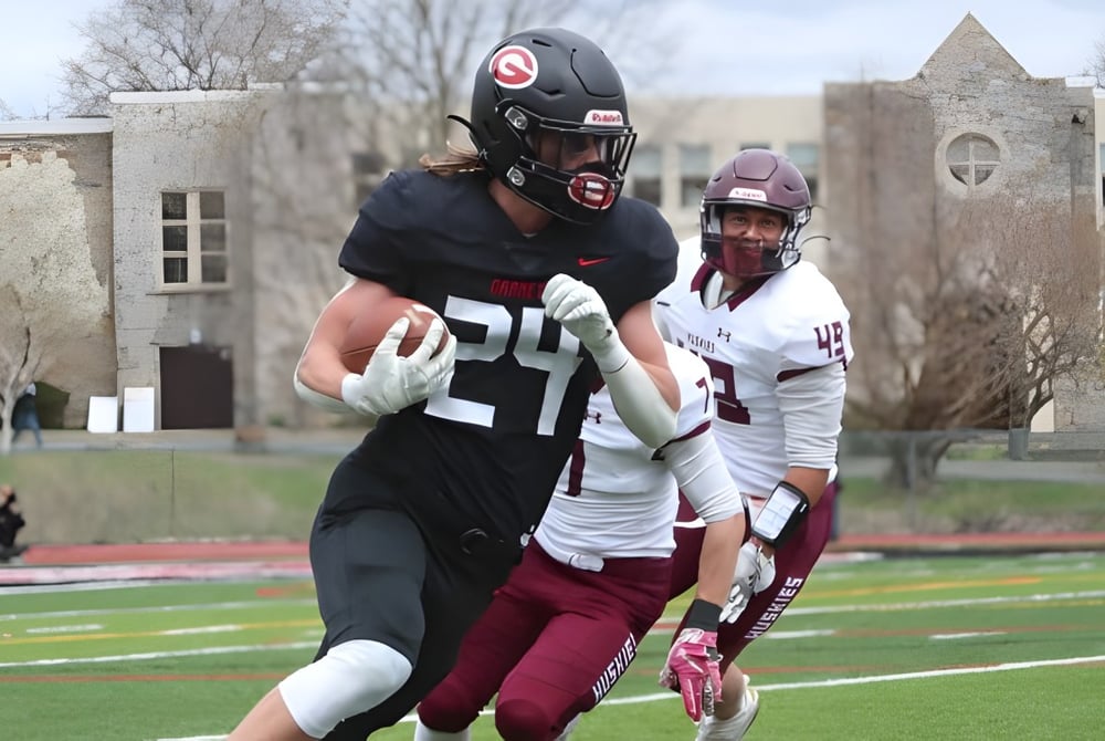 Zwei Fußballspieler spielen auf dem Sportfeld der St. Matthew High School vor Gebäuden im Hintergrund.